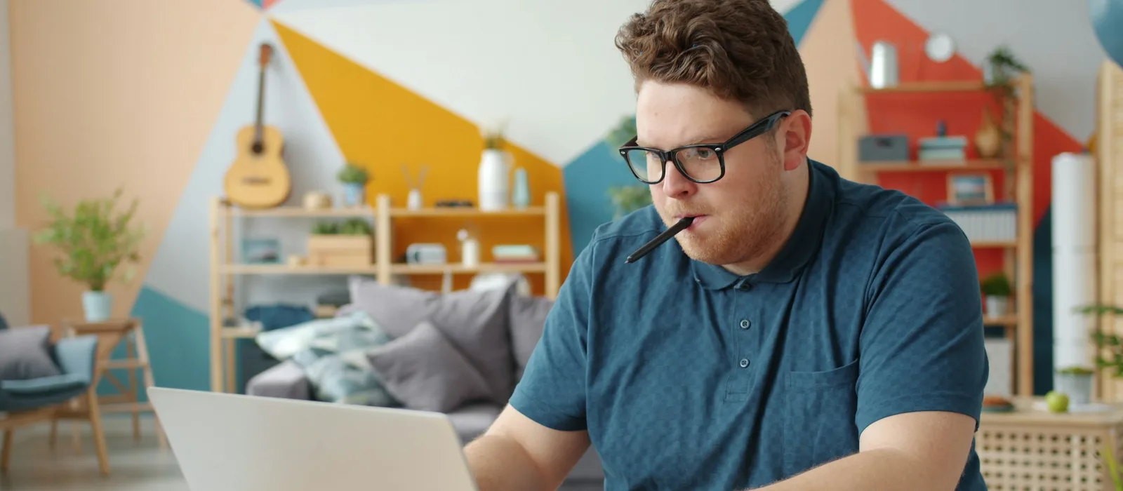 Mężczyzna uczy się samodzielnie przy laptopie i robi notatki.