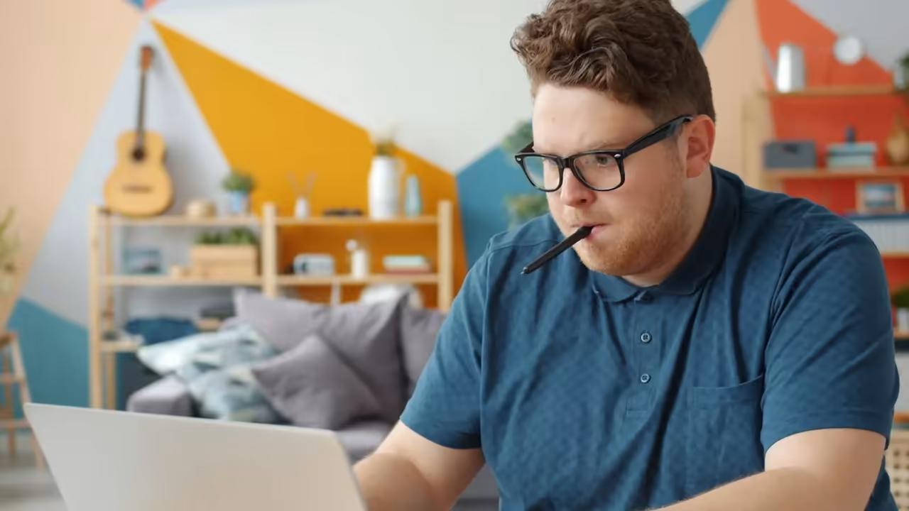 Mężczyzna uczy się samodzielnie przy laptopie i robi notatki.