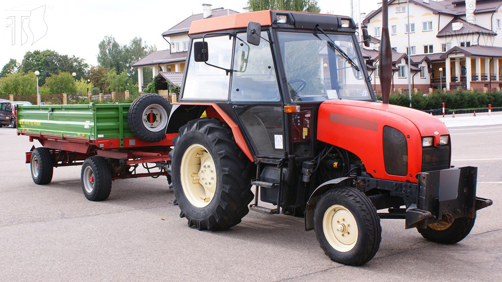 Materiał do pytania: W jaki sposób powinieneś obserwować drogę za ciągnikiem rolniczym z przyczepą w czasie cofania?