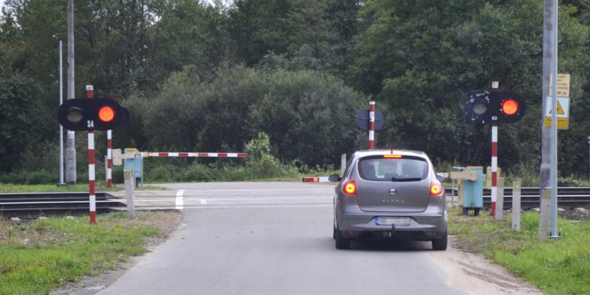 Materiał do pytania: Czy w tej sytuacji masz prawo ominąć poprzedzający pojazd wjeżdżając na część jezdni przeznaczoną dla przeciwnego kierunku ruchu, jeśli zdołasz zatrzymać się przed przejazdem kolejowym ?