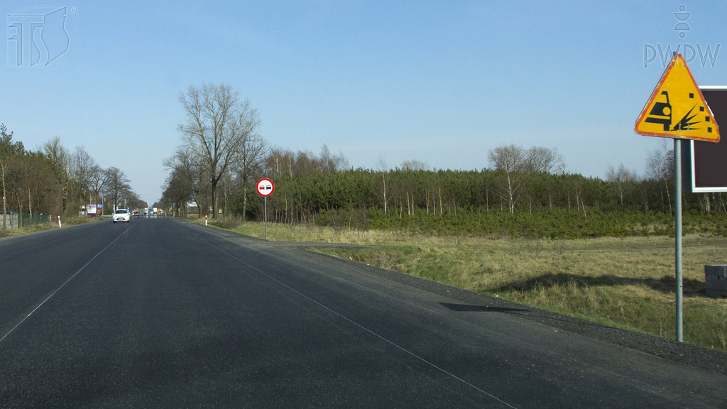 Materiał do pytania: Czy w przedstawionej sytuacji jesteś ostrzegany o drodze pokrytej żwirem, który może być wyrzucany spod kół jadących pojazdów?